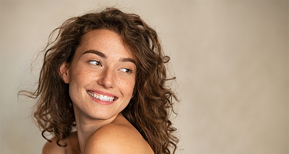 a beautiful smiling women with brown hair and freckles looking away