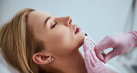 a woman receiving a dermal filler injection to the lips